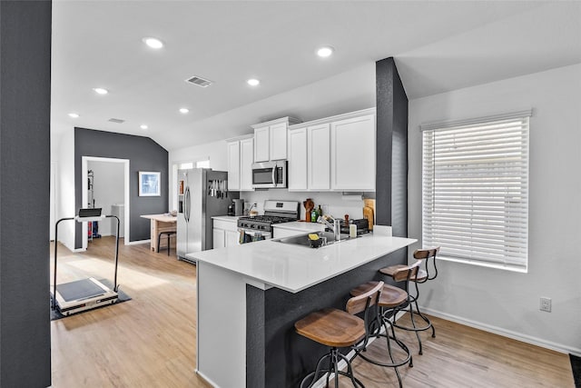 kitchen with lofted ceiling, white cabinets, sink, light hardwood / wood-style flooring, and stainless steel appliances