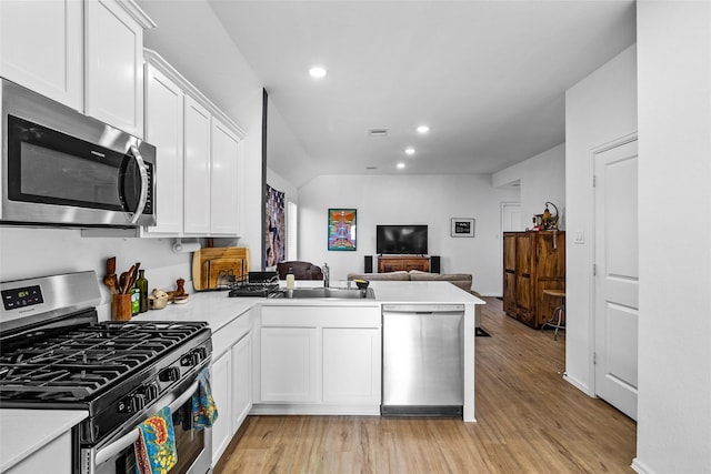 kitchen with kitchen peninsula, white cabinets, stainless steel appliances, and light wood-type flooring