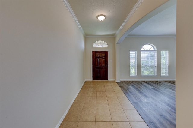 entryway featuring crown molding, a textured ceiling, and light wood-type flooring