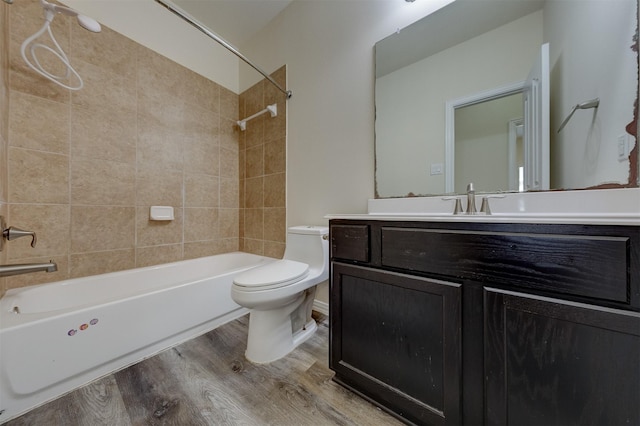 full bathroom with vanity, wood-type flooring, tiled shower / bath combo, and toilet