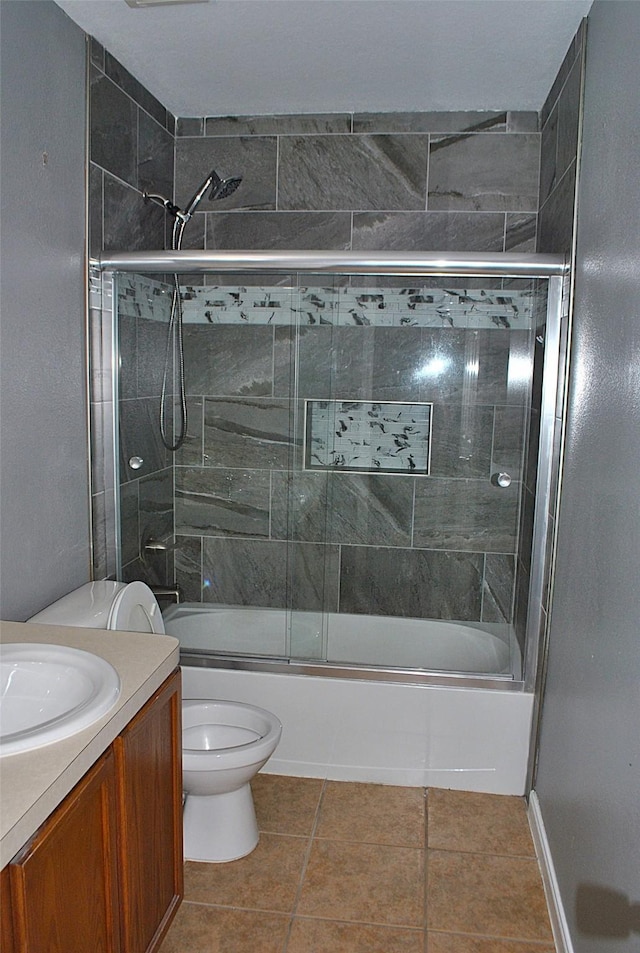 full bathroom featuring combined bath / shower with glass door, vanity, toilet, and tile patterned floors