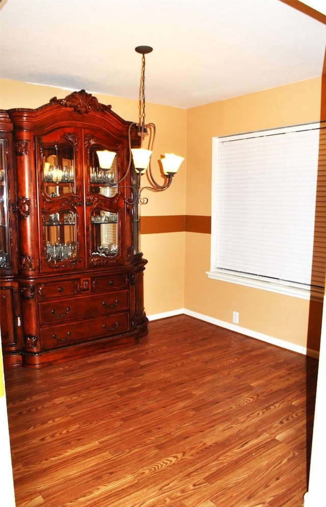 unfurnished dining area featuring wood-type flooring and a notable chandelier