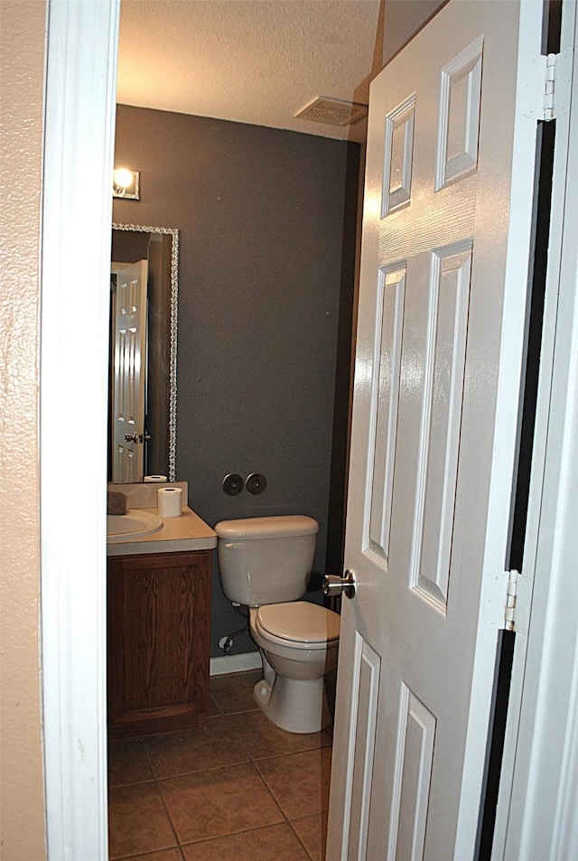 bathroom featuring a textured ceiling, vanity, toilet, and tile patterned floors