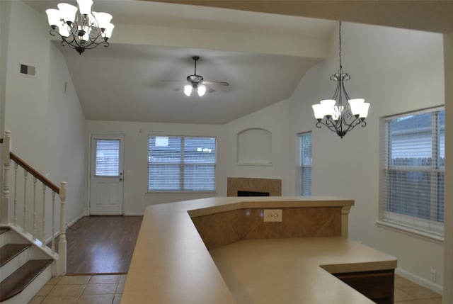 kitchen with vaulted ceiling, light countertops, a tile fireplace, and visible vents