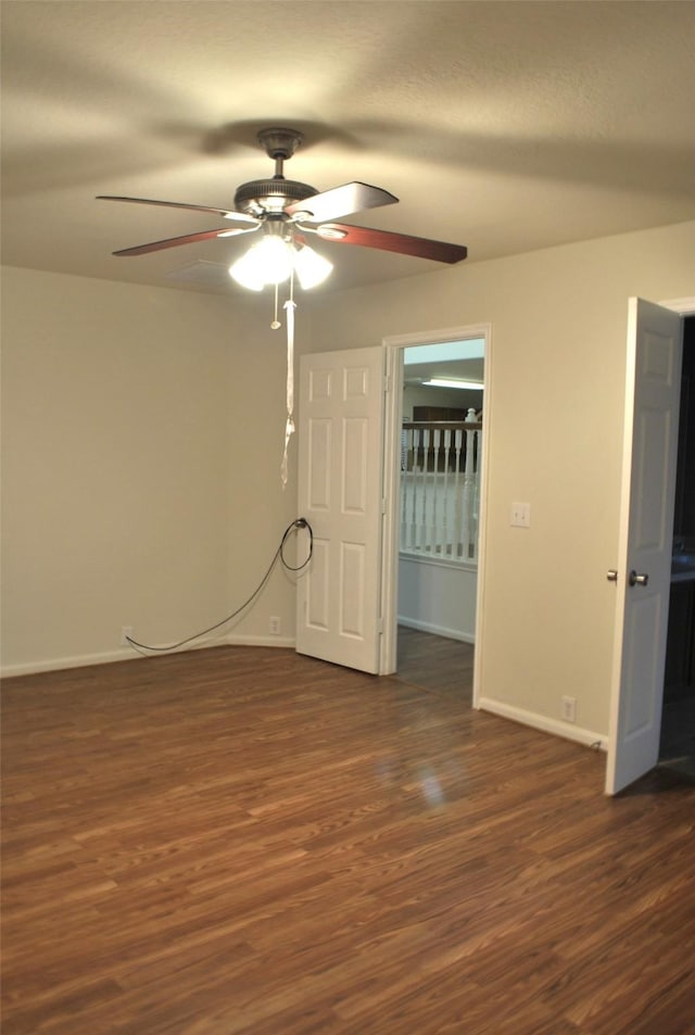 interior space featuring dark wood-type flooring, a ceiling fan, and baseboards