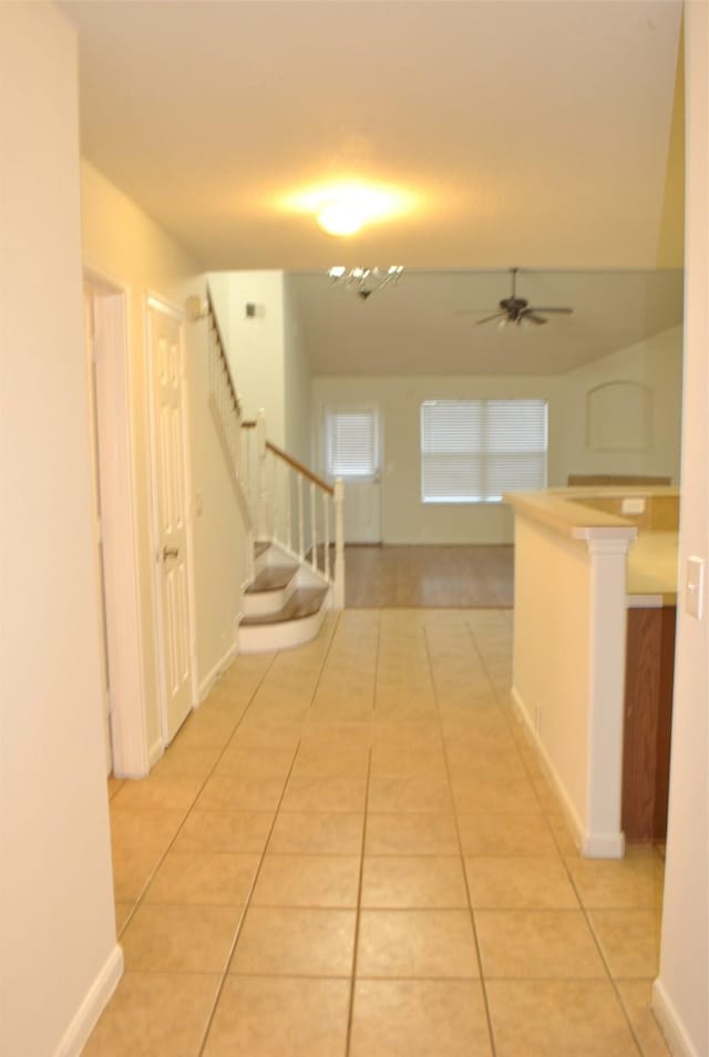 corridor featuring light tile patterned floors and stairs