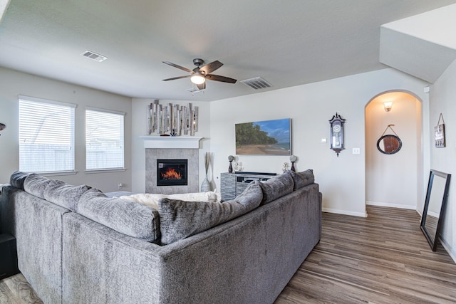 living room featuring hardwood / wood-style flooring, ceiling fan, and a tiled fireplace