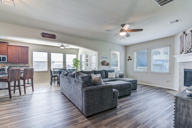 living room with a tile fireplace, dark hardwood / wood-style flooring, and a textured ceiling