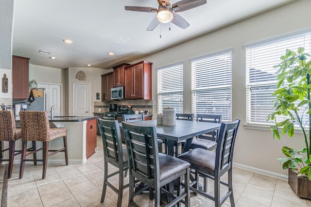 tiled dining room with plenty of natural light, ceiling fan, and sink