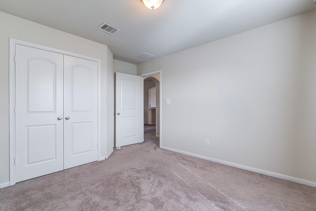 unfurnished bedroom with light colored carpet and a closet