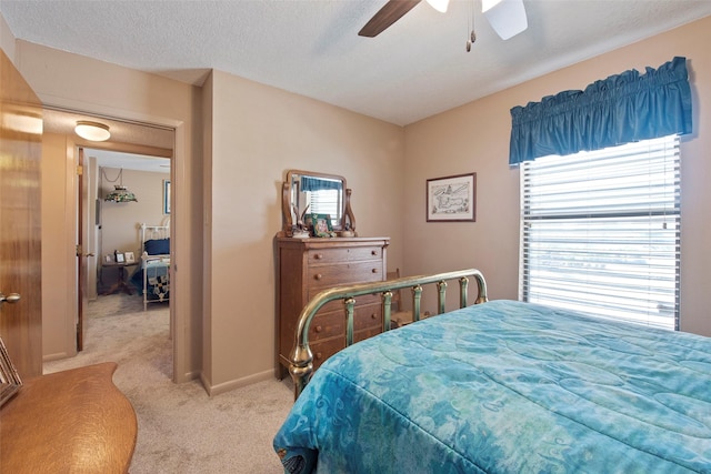 bedroom featuring light carpet, a textured ceiling, and ceiling fan