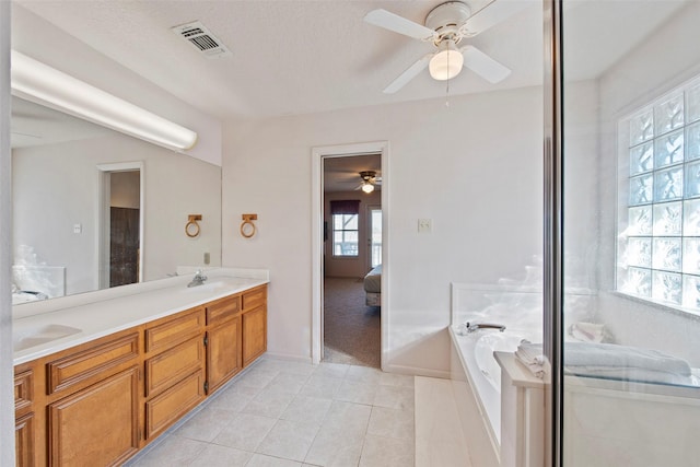 bathroom with tile patterned floors, tiled bath, vanity, and a healthy amount of sunlight