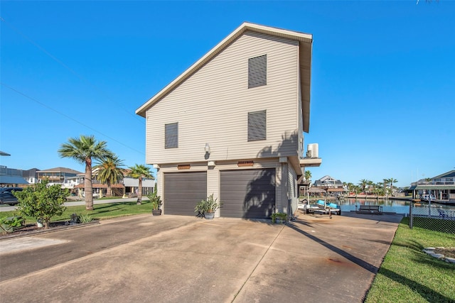 view of side of property featuring a yard, a water view, and a garage