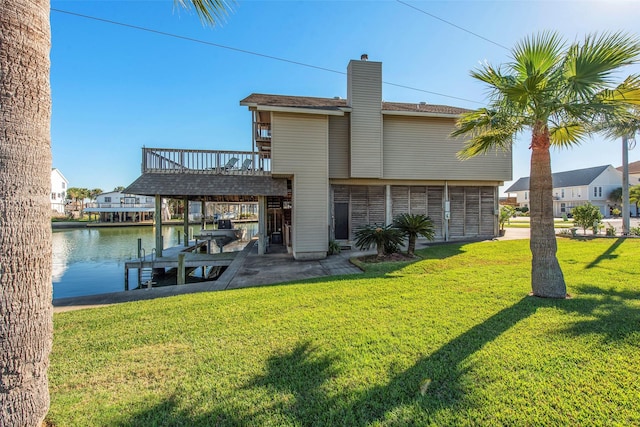 back of property featuring a deck with water view and a lawn