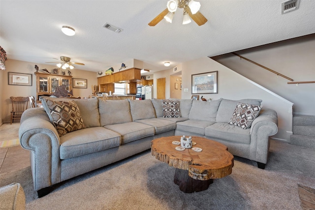 carpeted living room featuring ceiling fan and a textured ceiling