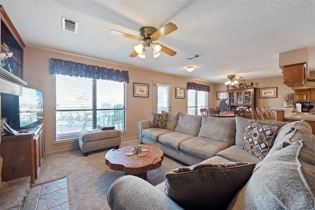 carpeted living room featuring ceiling fan and a textured ceiling