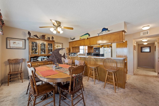 dining room featuring light carpet, a textured ceiling, and ceiling fan