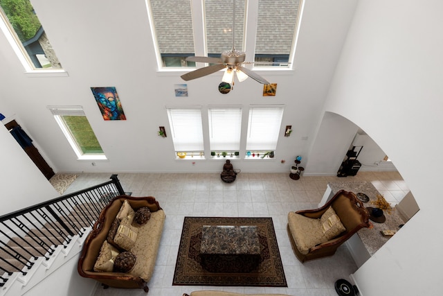 tiled living room with plenty of natural light, ceiling fan, and a high ceiling