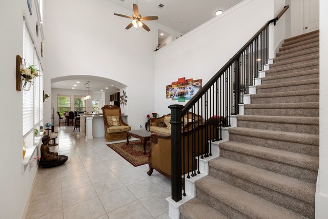 staircase featuring tile patterned flooring, ceiling fan, and a high ceiling