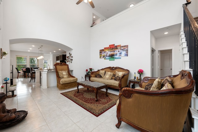 tiled living room featuring ceiling fan and a high ceiling