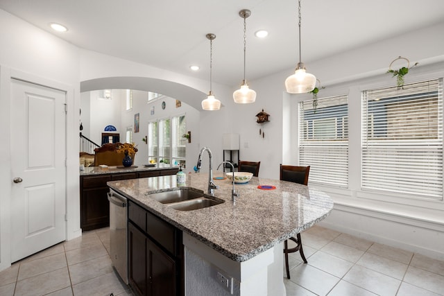 kitchen with dishwasher, sink, light stone counters, an island with sink, and decorative light fixtures