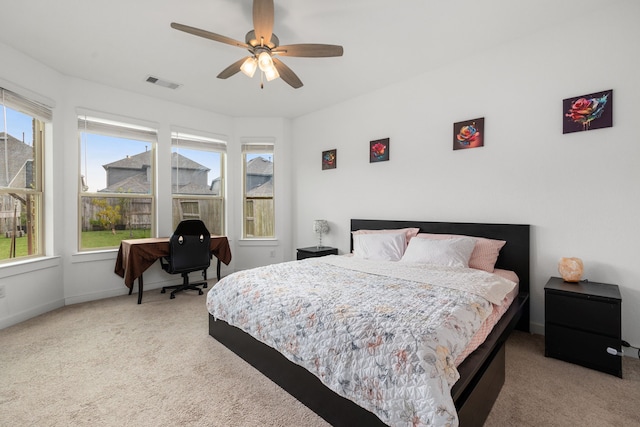 bedroom featuring multiple windows, ceiling fan, and light carpet