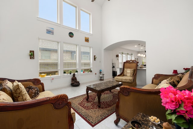 living room with a wealth of natural light, light tile patterned flooring, a high ceiling, and an inviting chandelier