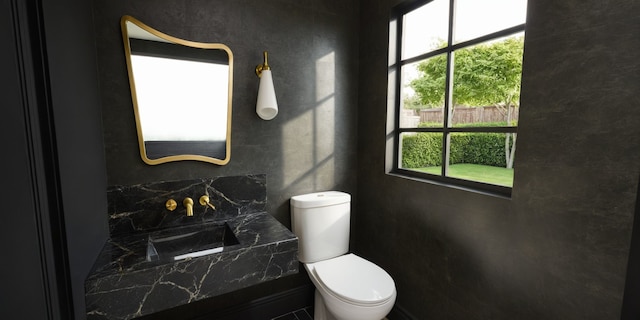 half bathroom with a sink, backsplash, and toilet