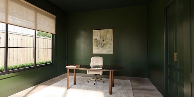 office area featuring a healthy amount of sunlight, a decorative wall, and light wood finished floors