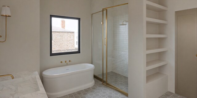 bathroom with a freestanding bath, built in shelves, a stall shower, and a sink