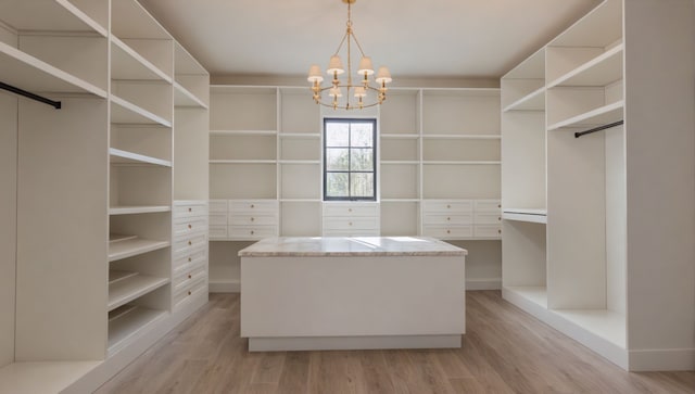 walk in closet featuring light wood finished floors and an inviting chandelier