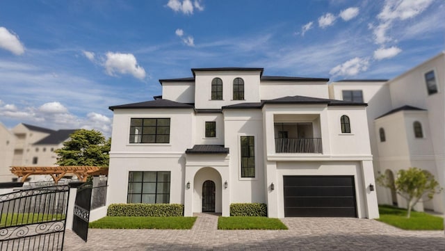 view of front facade featuring a balcony, a garage, fence, decorative driveway, and stucco siding