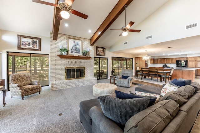 carpeted living room featuring beamed ceiling, ceiling fan with notable chandelier, a fireplace, and high vaulted ceiling