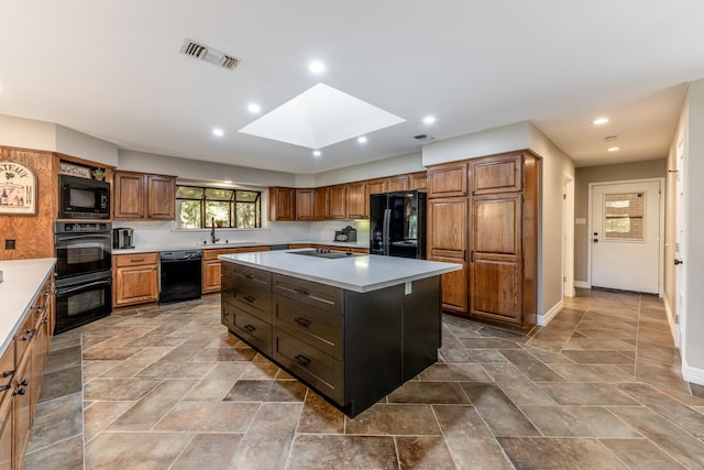 kitchen with a skylight, a center island, black appliances, and sink