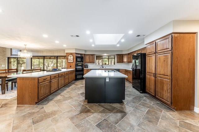 kitchen with a spacious island, a wealth of natural light, black appliances, and a skylight