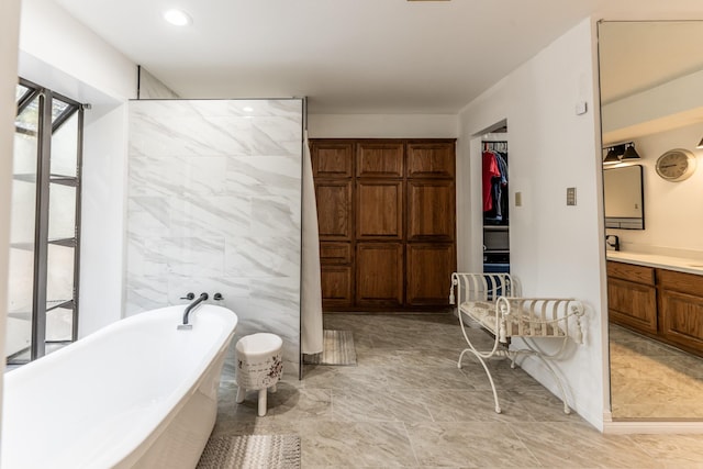 bathroom with a washtub, vanity, and tile walls