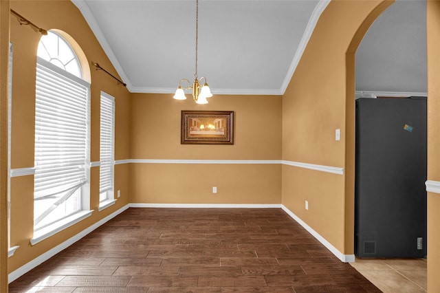 empty room featuring a chandelier, crown molding, and wood-type flooring