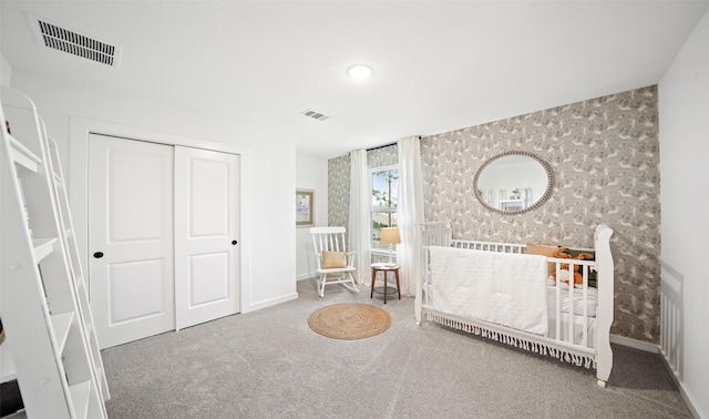 carpeted bedroom with a crib and a closet