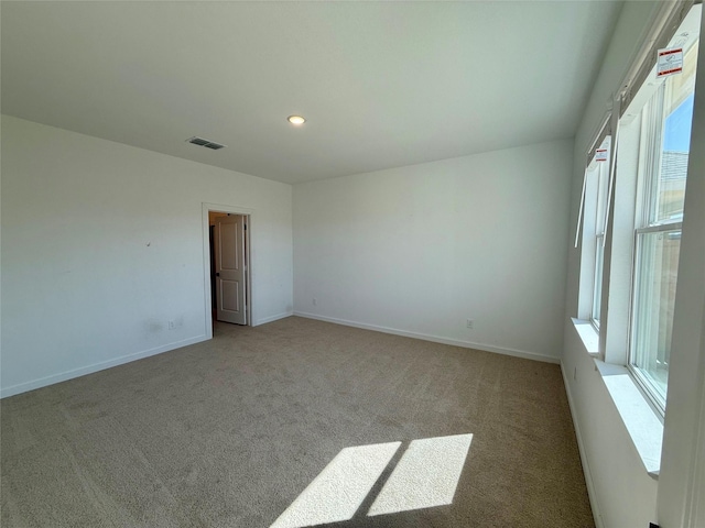 carpeted empty room with baseboards, visible vents, and recessed lighting