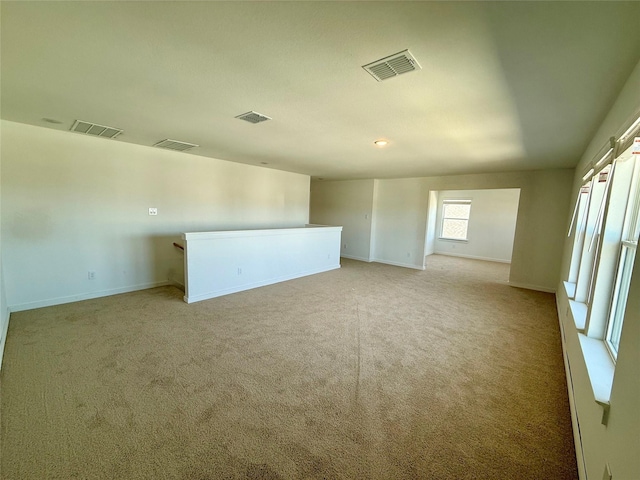 empty room featuring light carpet, visible vents, and baseboards