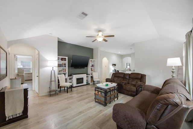 living room with ceiling fan, light hardwood / wood-style floors, and vaulted ceiling