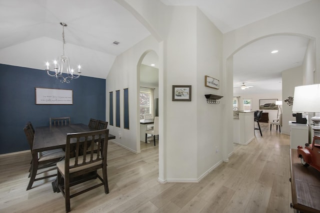 dining space with ceiling fan with notable chandelier, light hardwood / wood-style floors, and lofted ceiling