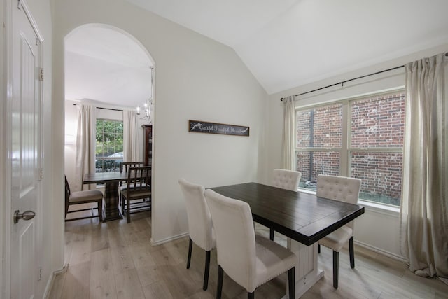 dining space featuring light hardwood / wood-style floors, lofted ceiling, and an inviting chandelier