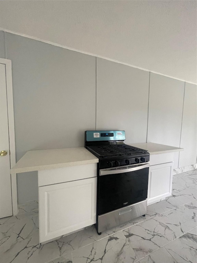 kitchen with kitchen peninsula, white cabinetry, and stainless steel gas range oven