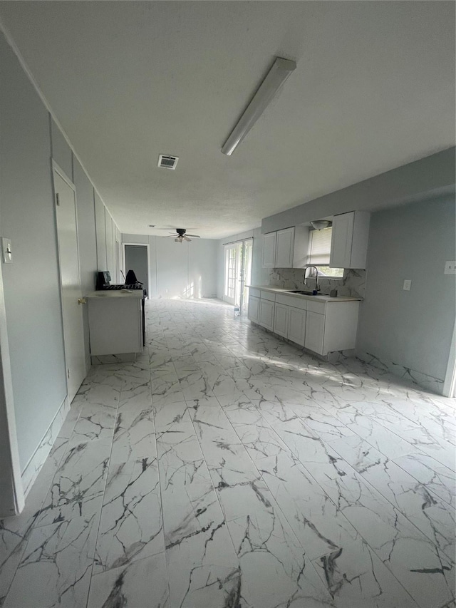 unfurnished living room featuring ceiling fan and sink