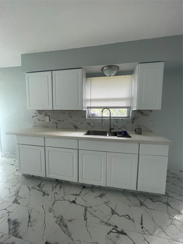 kitchen with white cabinetry, sink, and tasteful backsplash