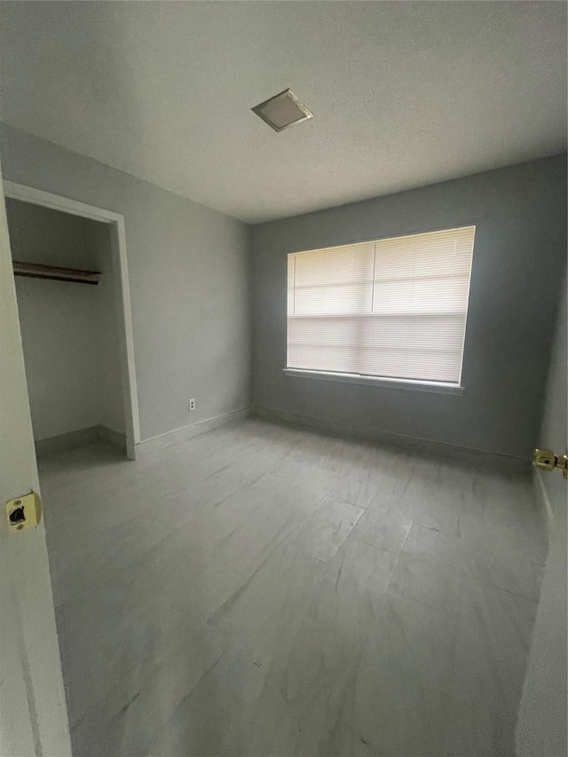 unfurnished bedroom featuring a textured ceiling and a closet