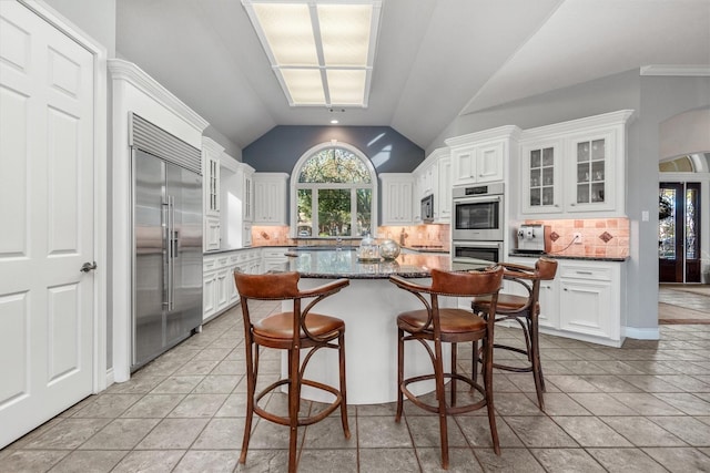 kitchen featuring decorative backsplash, a kitchen island, white cabinets, and appliances with stainless steel finishes