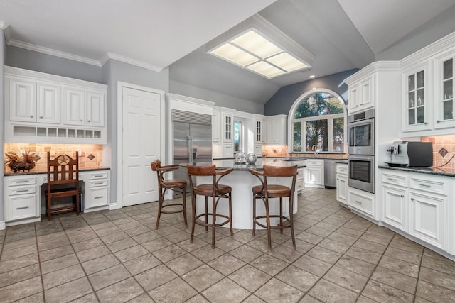 kitchen featuring backsplash, white cabinetry, a kitchen bar, and appliances with stainless steel finishes