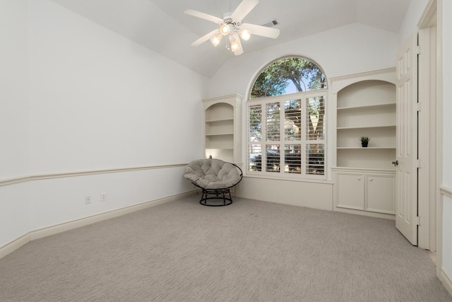 spare room featuring light carpet, built in features, ceiling fan, and vaulted ceiling